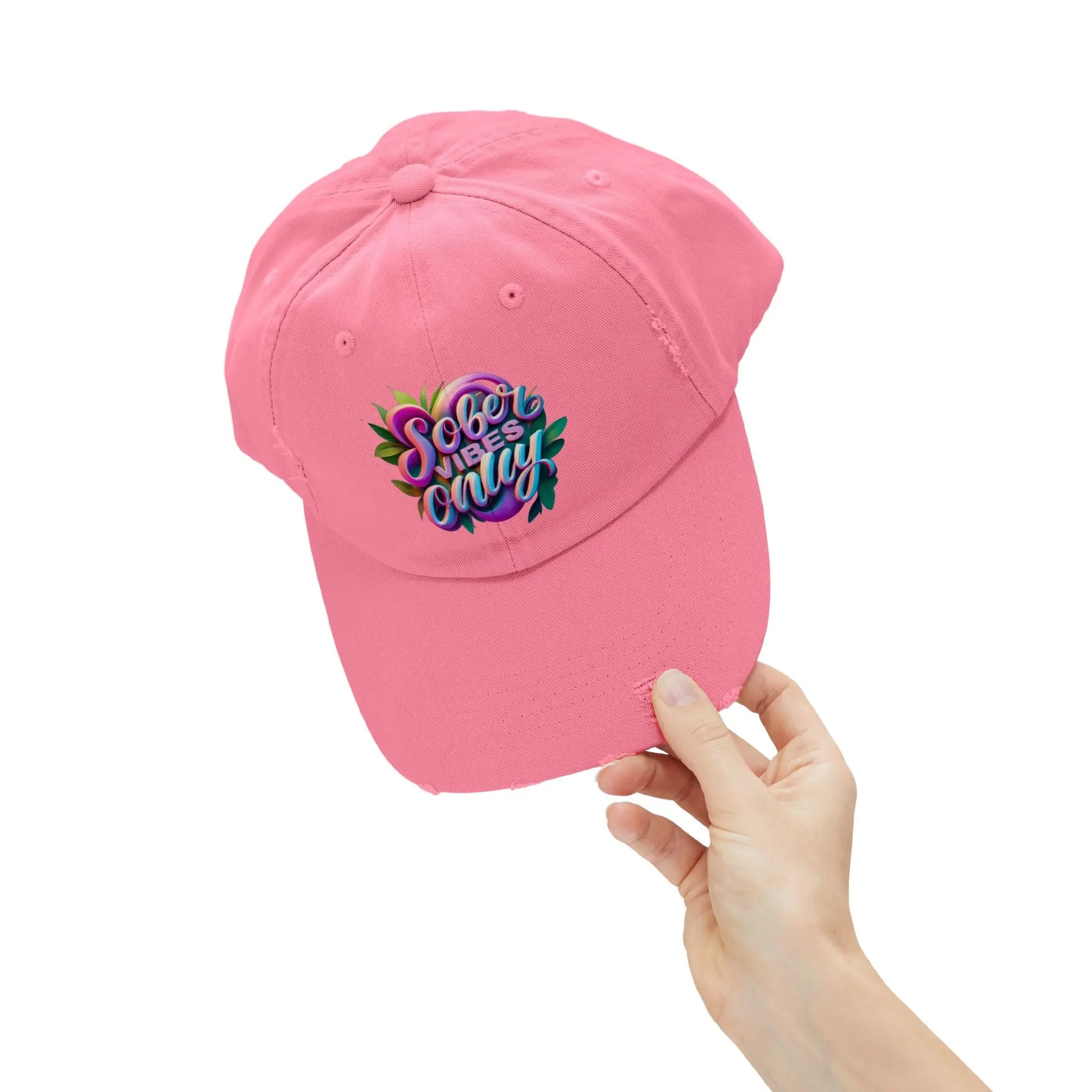 Pink Trucker Hat with colorful text held by a hand on a white background